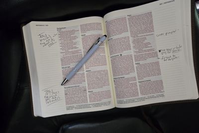 An open Bible at Matthew, with handwritten study notes and a pen