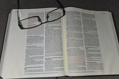 Reading glasses on an open Bible at Luke 8, over the story of the man called Legion